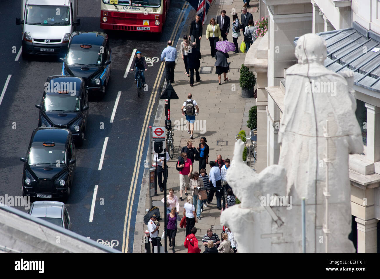 View of taxis, people and buses on Ludgate Hill from St Pauls Cathedral, with statue to the right. Stock Photo