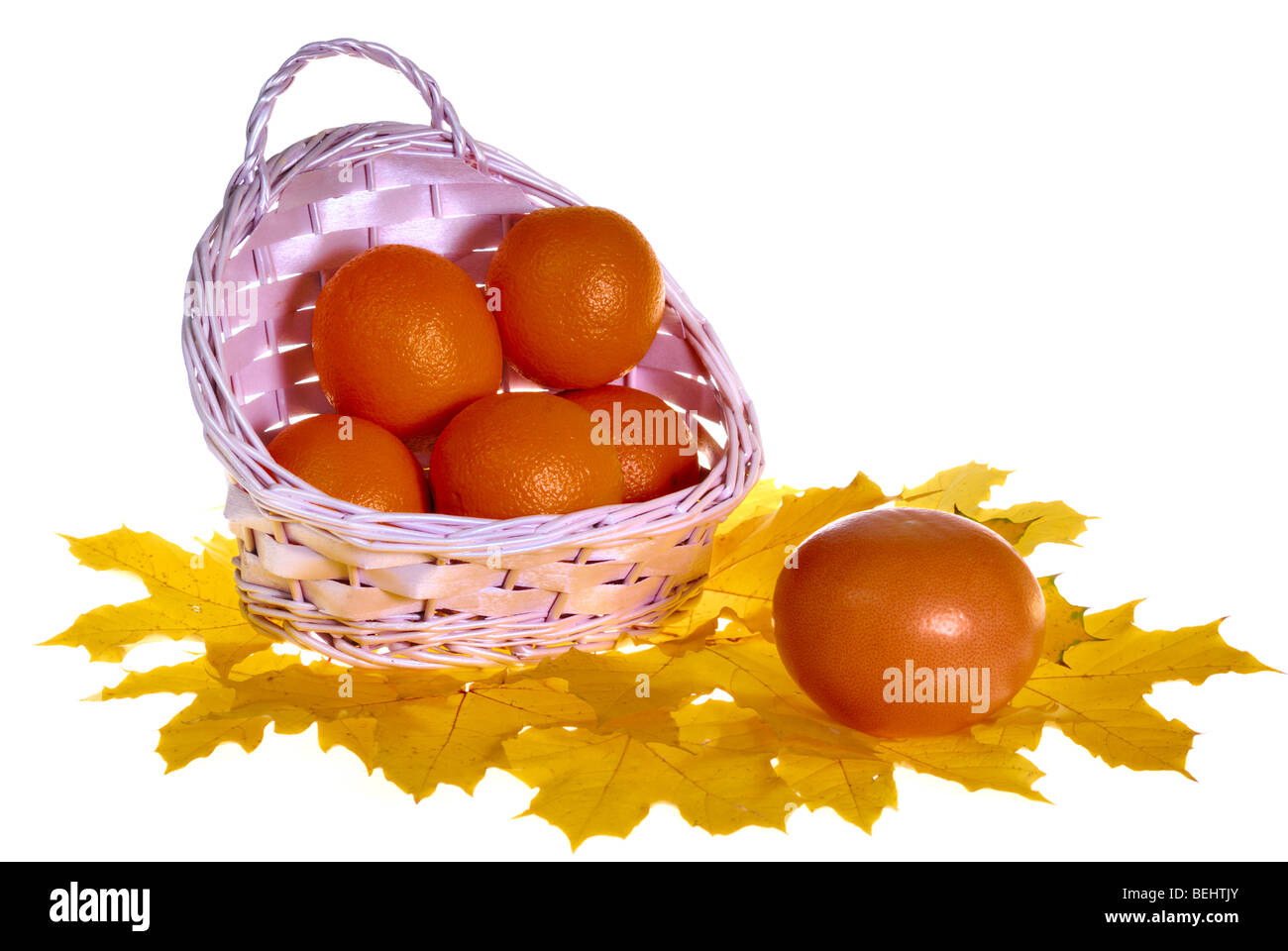 Oranges in basket on maple leaves isolated on white Stock Photo