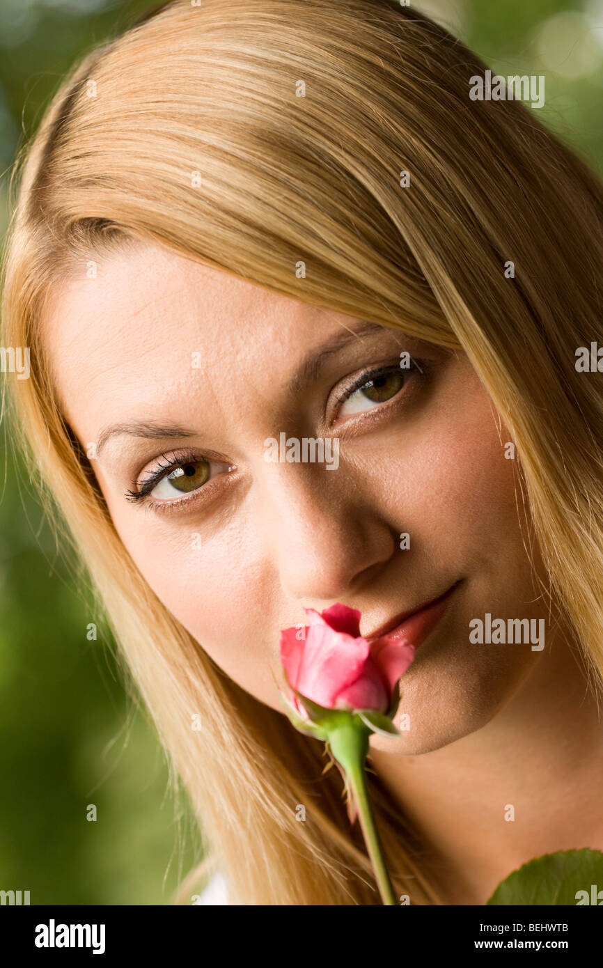 Young woman smelling the pink rose Stock Photo - Alamy