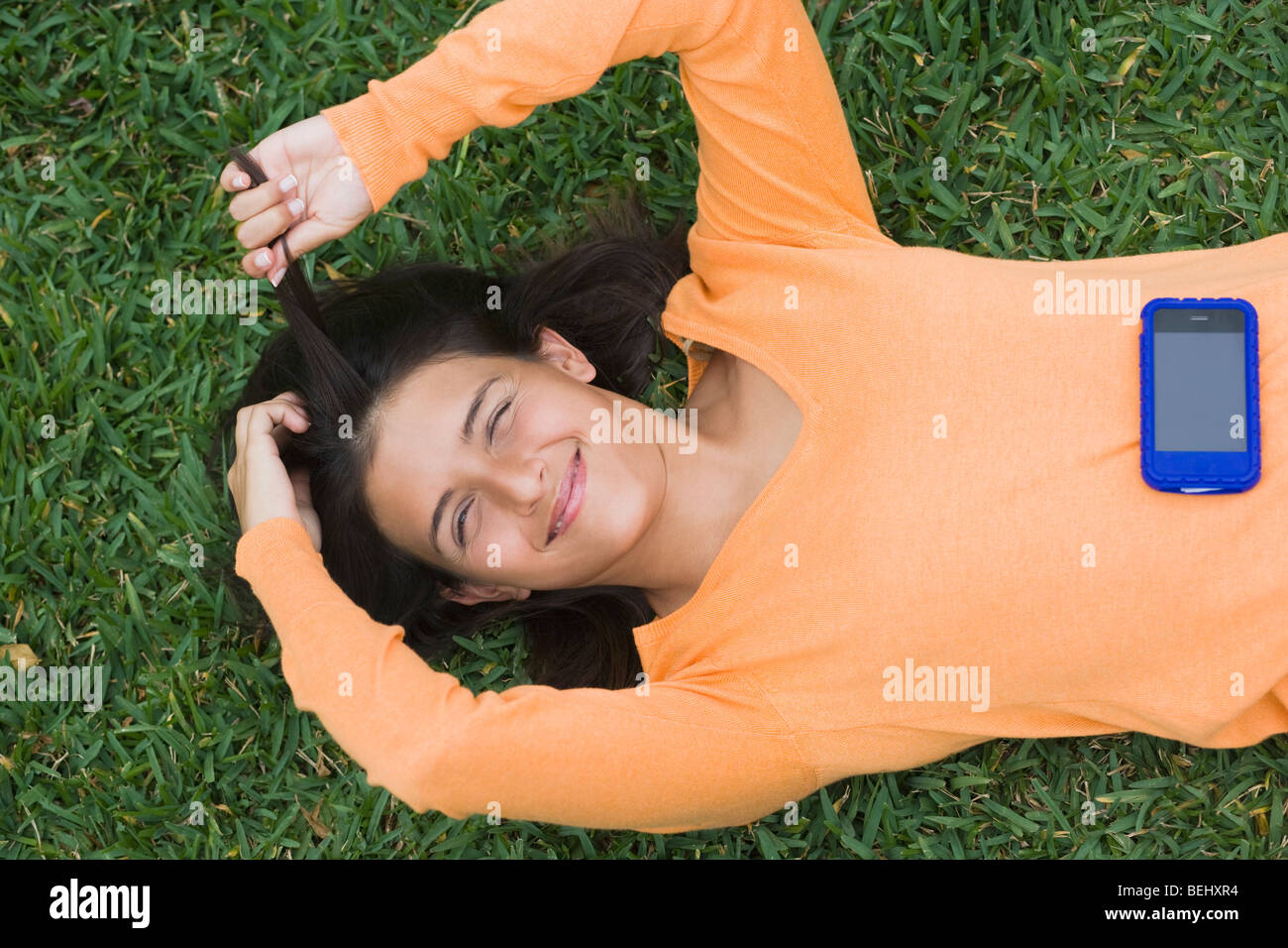 Teenage girl lying in a park with a mobile phone Stock Photo