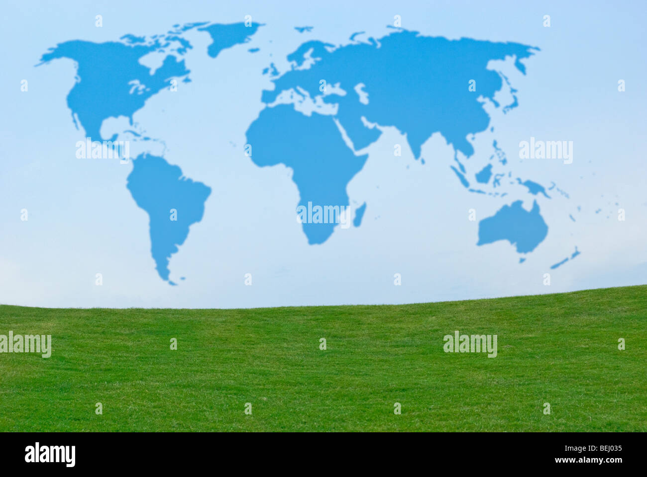 Outline of world map in blue sky above green grass Stock Photo