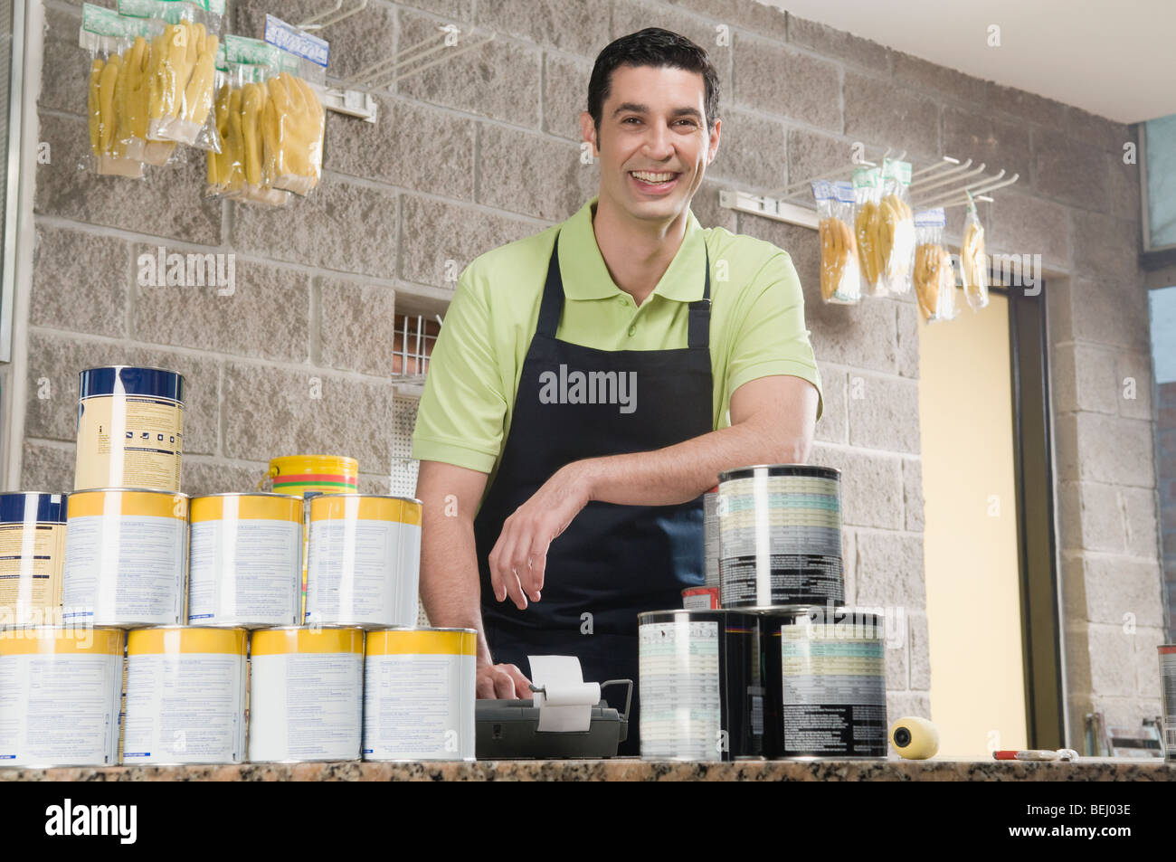 Sales clerk standing at the counter of a paint shop and smiling Stock