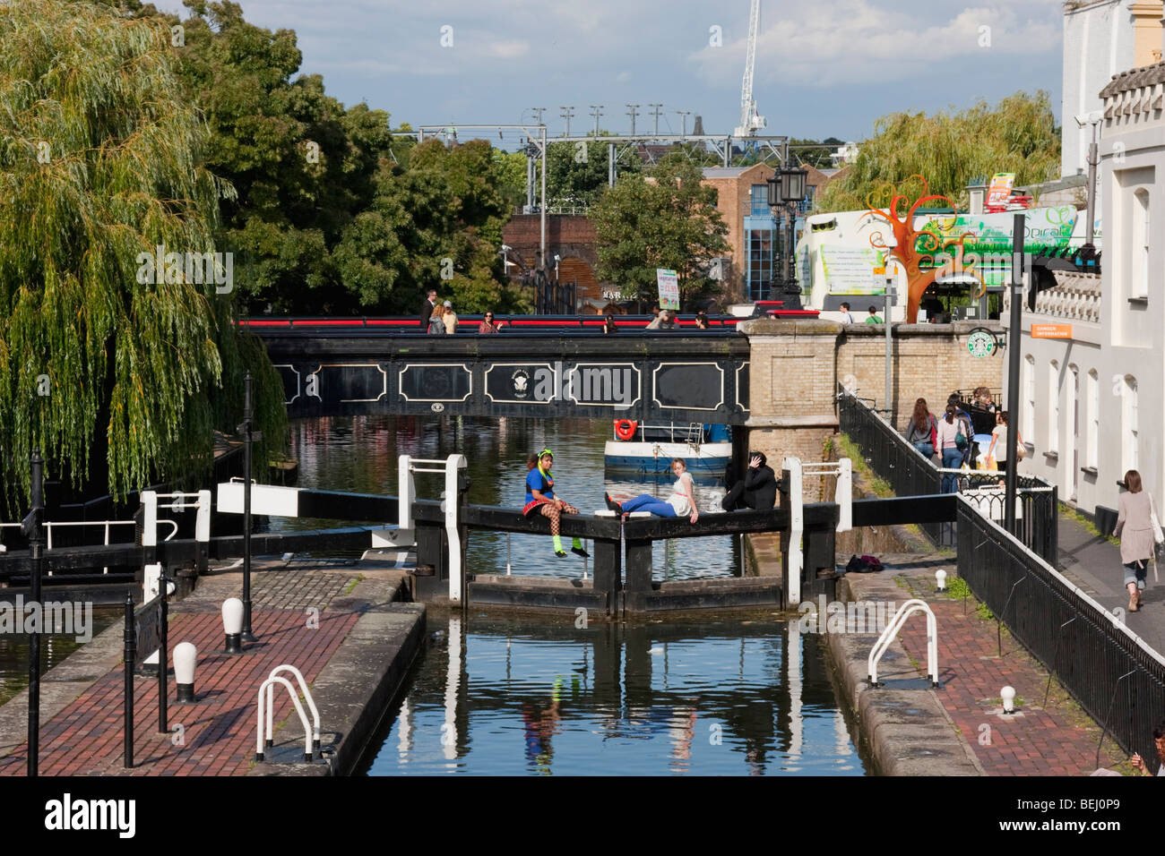 Three young people sitting on the Regent's Canal lock gate in Camden ...