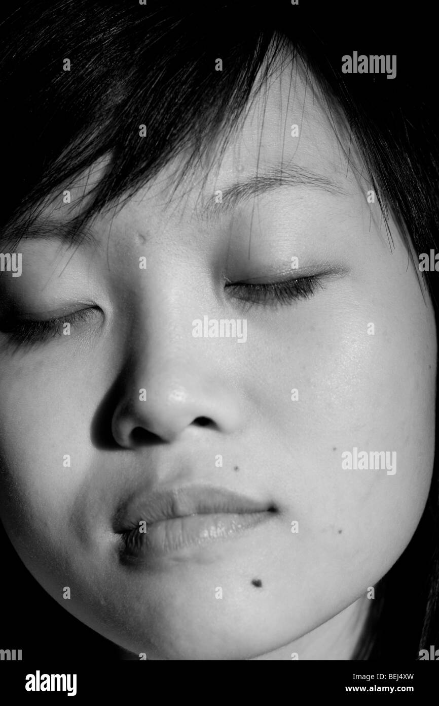 Serene and calming image of a young Asian woman with her eyes closed ...