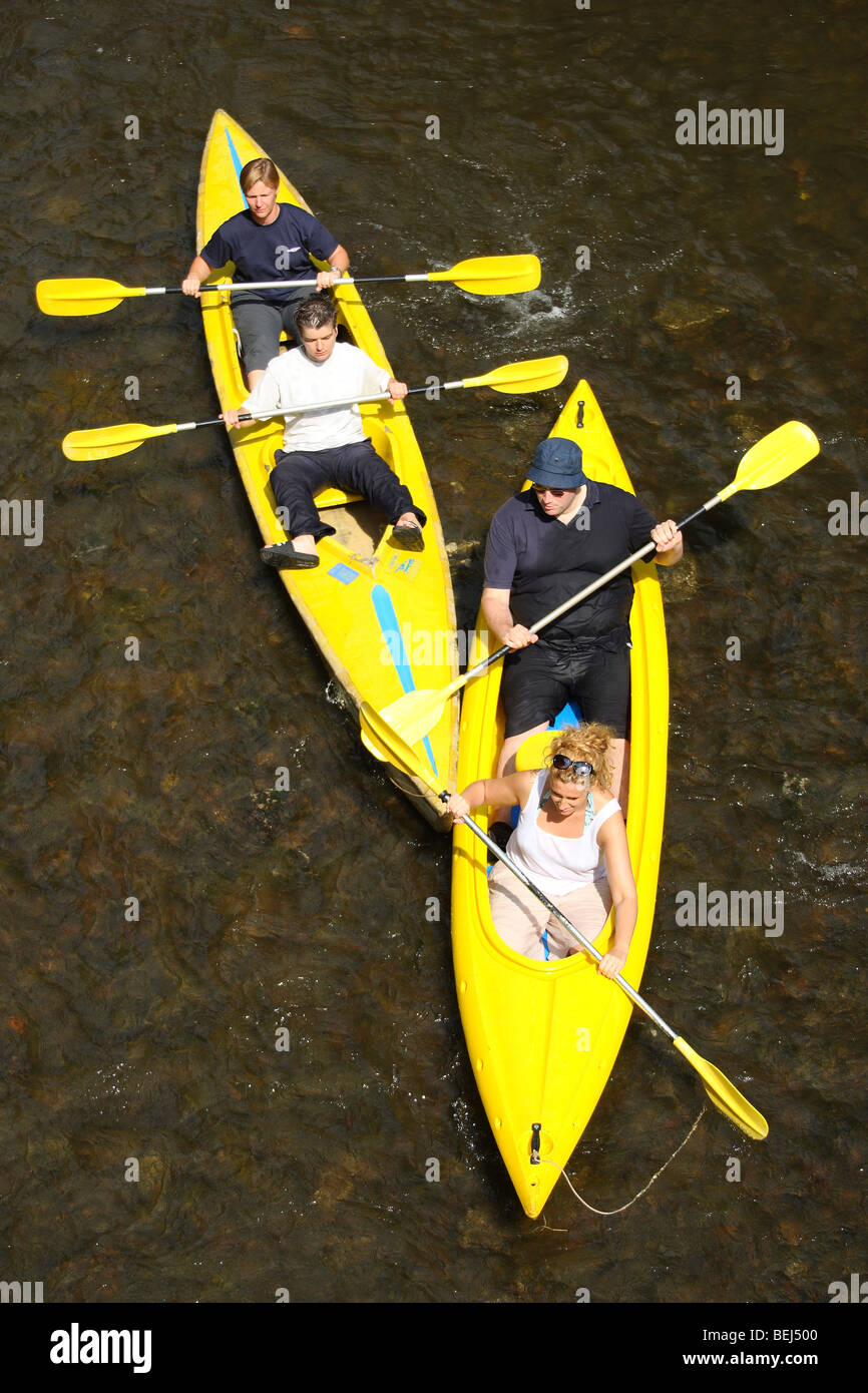 Kayakers / canoers kayaking / canoeing in yellow kayaks / canoes on the river Lesse in the Belgian Ardennes, Belgium Stock Photo