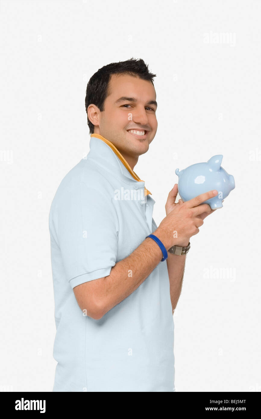 Portrait of a young man holding a piggy bank and smiling Stock Photo ...