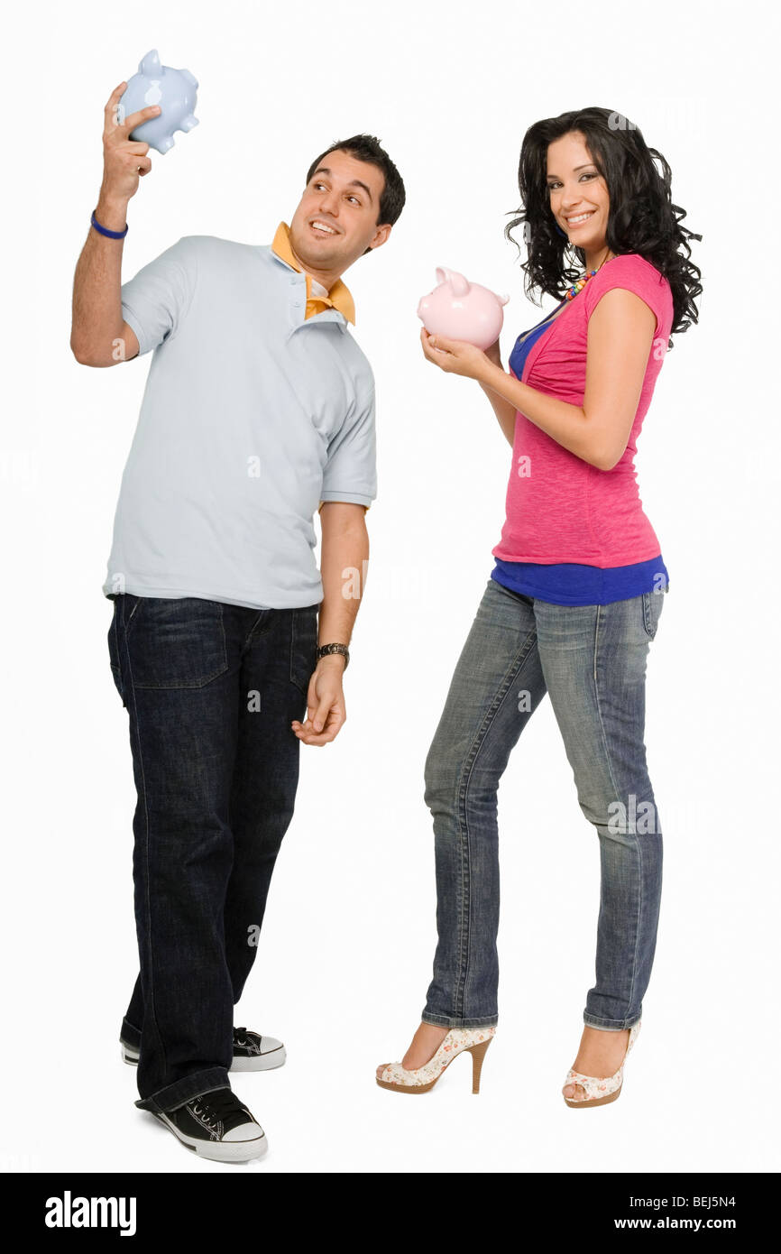 Young couple holding piggy banks and smiling Stock Photo - Alamy
