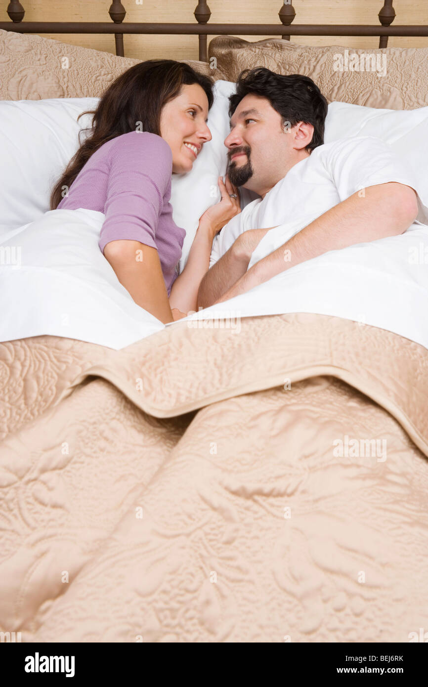 High angle view of a mid adult couple lying on the bed and looking at ...