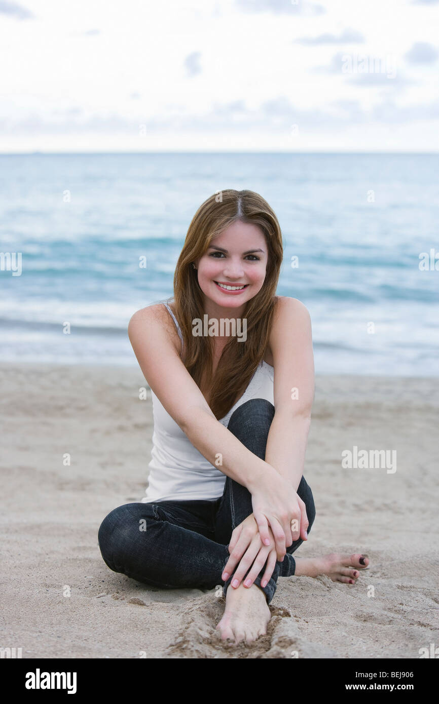 Portrait of a young woman sitting on the beach Stock Photo - Alamy