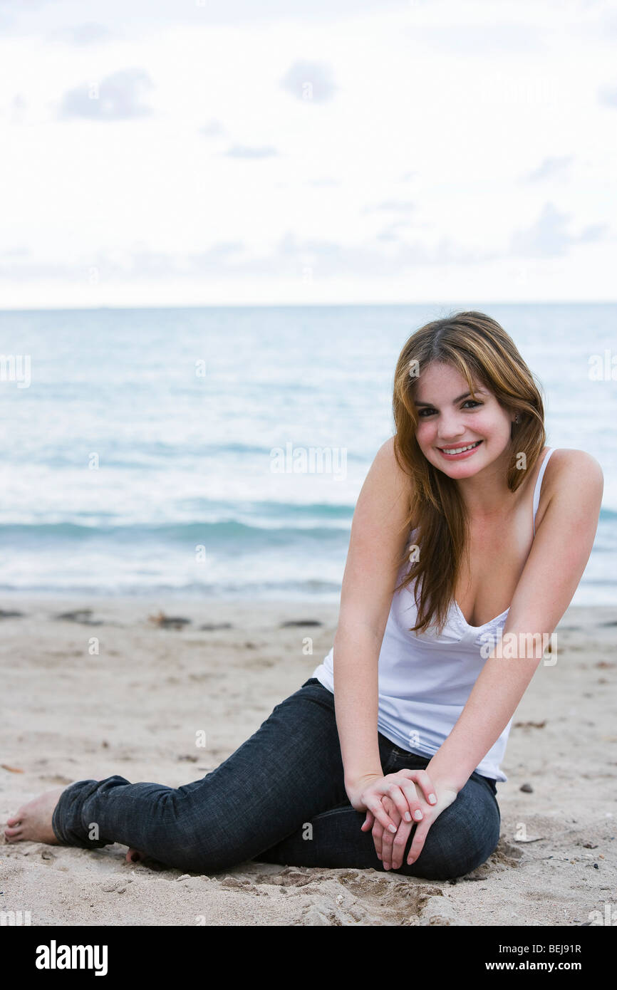 Portrait of a young woman sitting on the beach and smiling Stock Photo ...