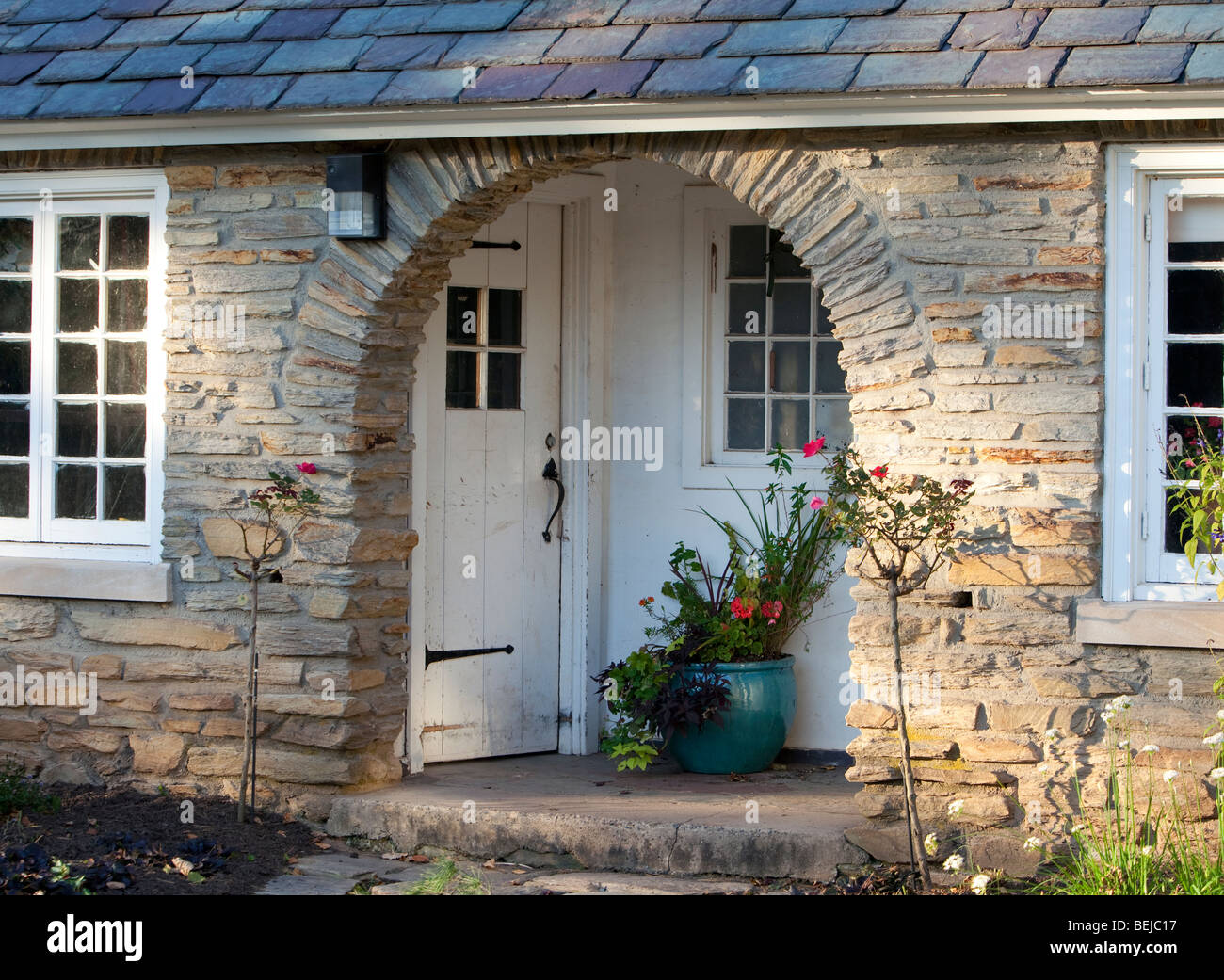 A recessed entrance with an archway and potted plants into an old