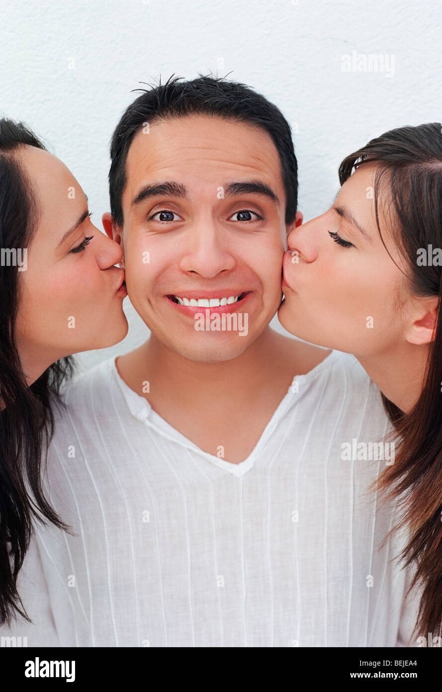 Young man being kissed by two young women Stock Photo Alamy