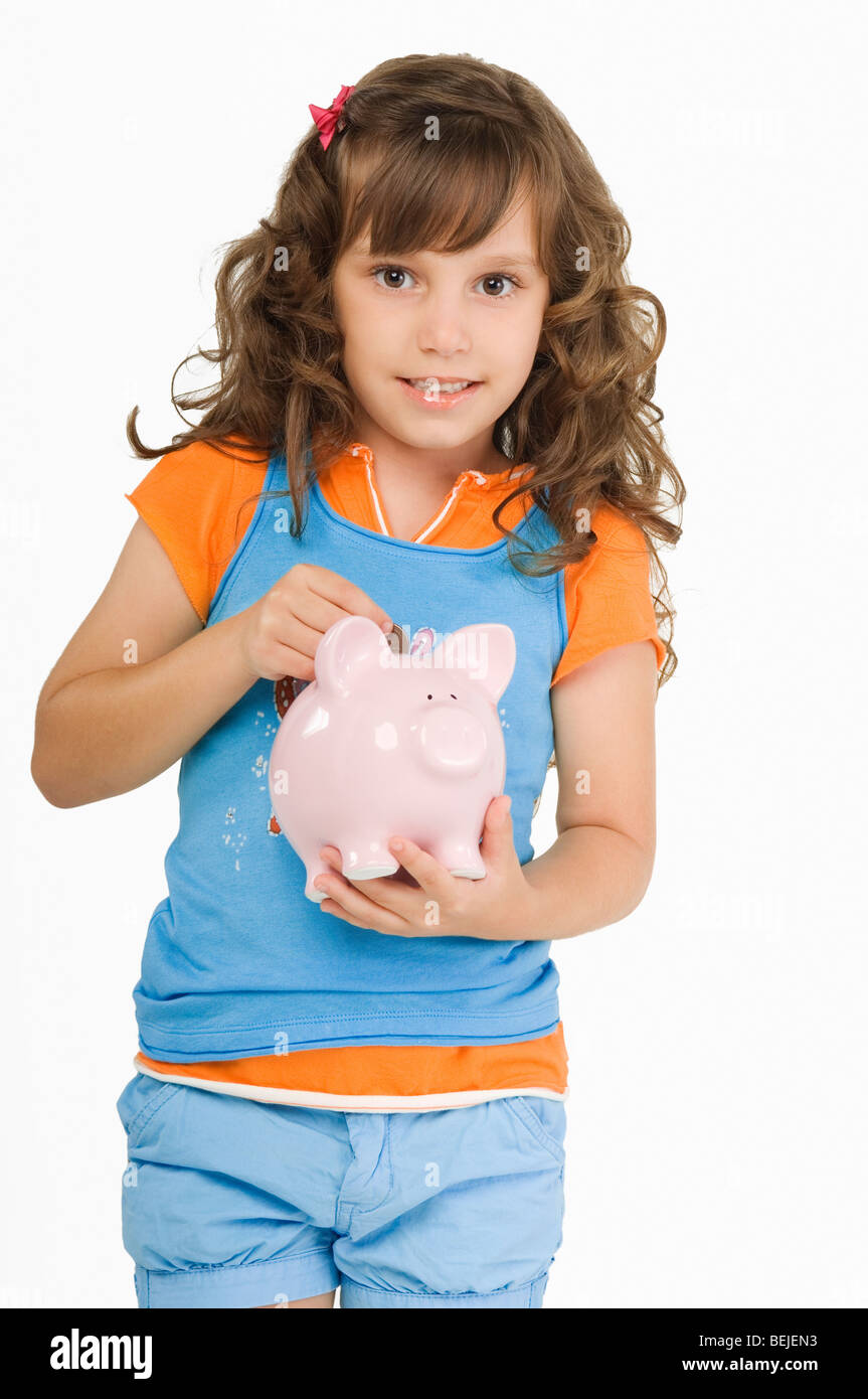 Close-up of a girl putting a coin into a piggy bank Stock Photo - Alamy