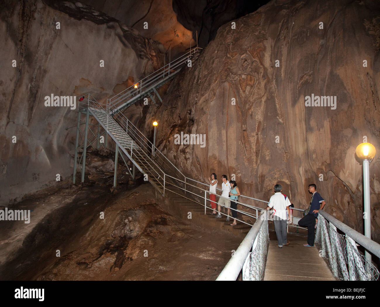 Gua Tempurung cave interior showing large stalacmite and tourists on walkways. Stock Photo