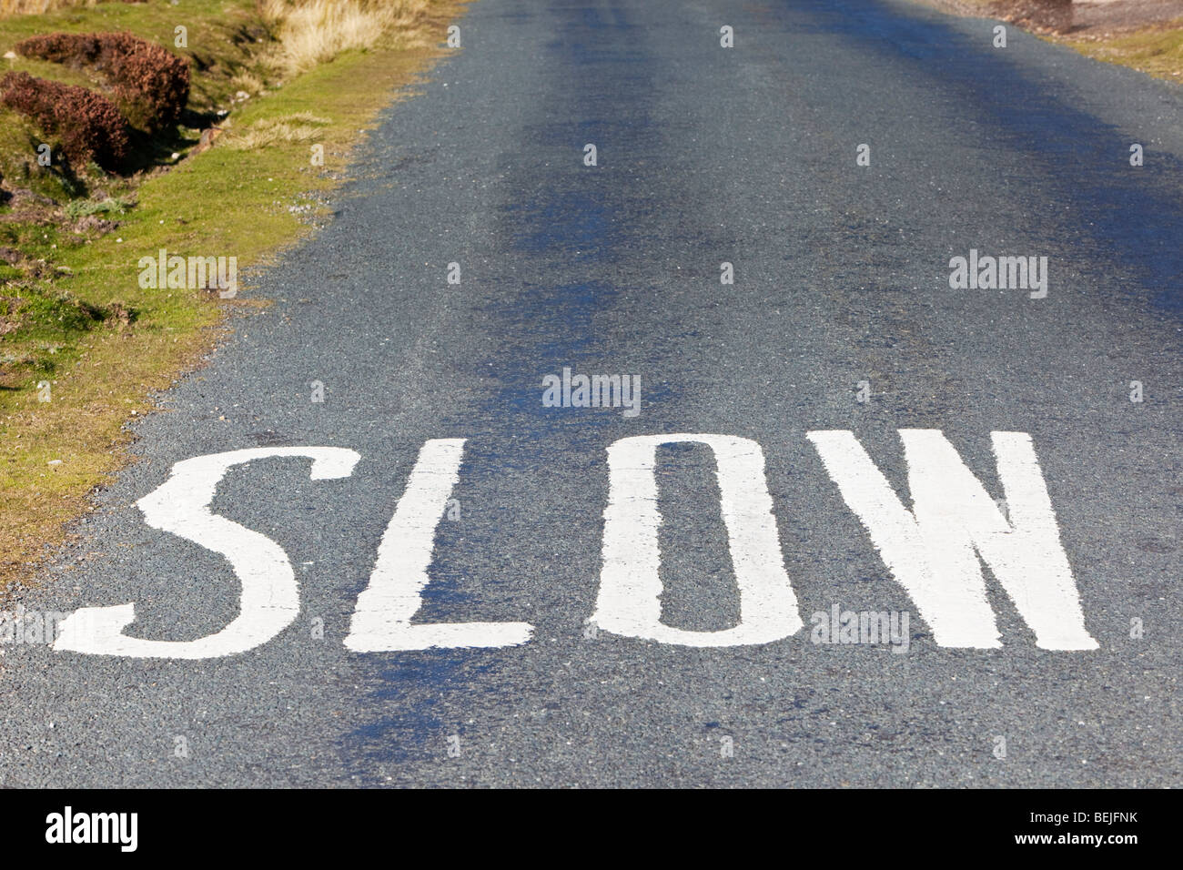SLOW warning sign road markings painted on road surface England UK Stock Photo