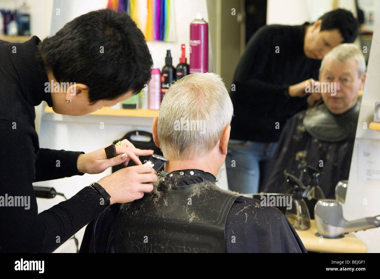 A hairdresser trimming a mans hair at a salon in UK Stock Photo Alamy