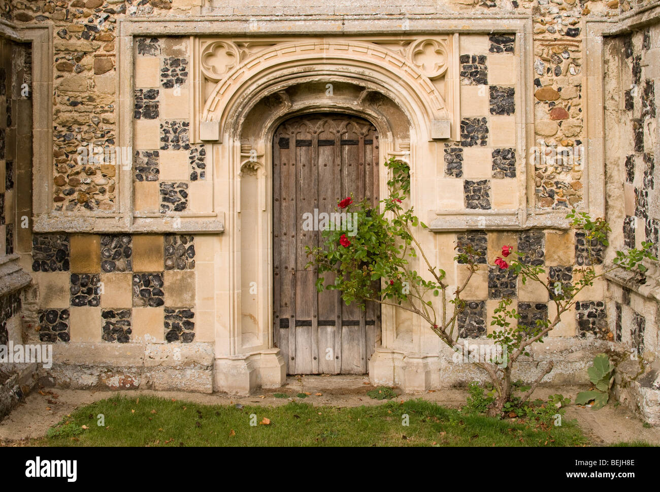 An old wooden door in the ornamental doorway of a church in Cavendish, Suffolk, England Stock Photo