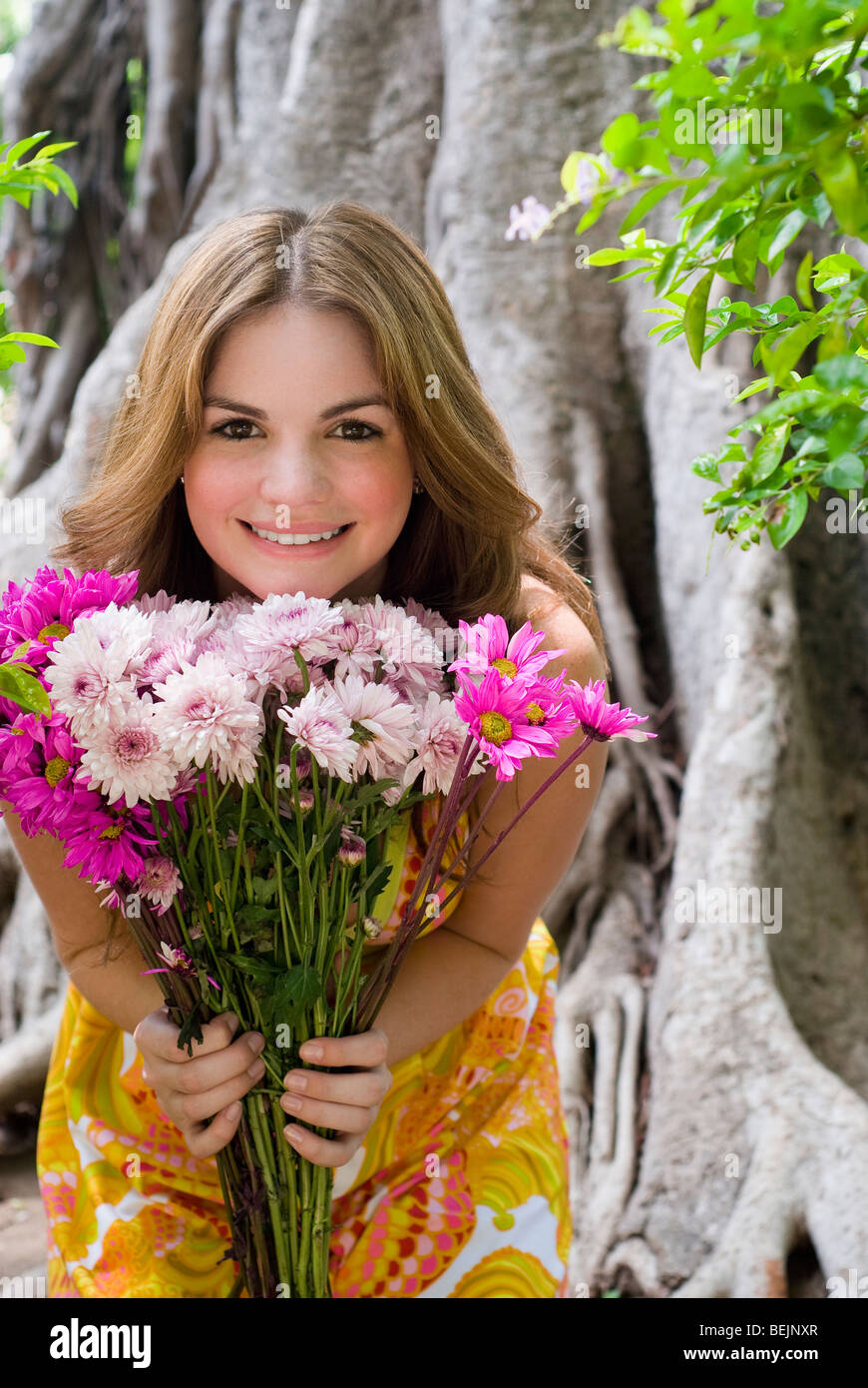 Portrait of a young woman showing a bouquet of flowers and smiling ...
