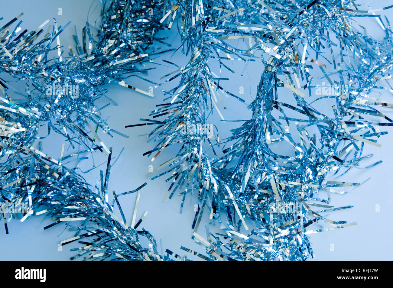 Blue Christmas tinsel on a pale blue background Stock Photo