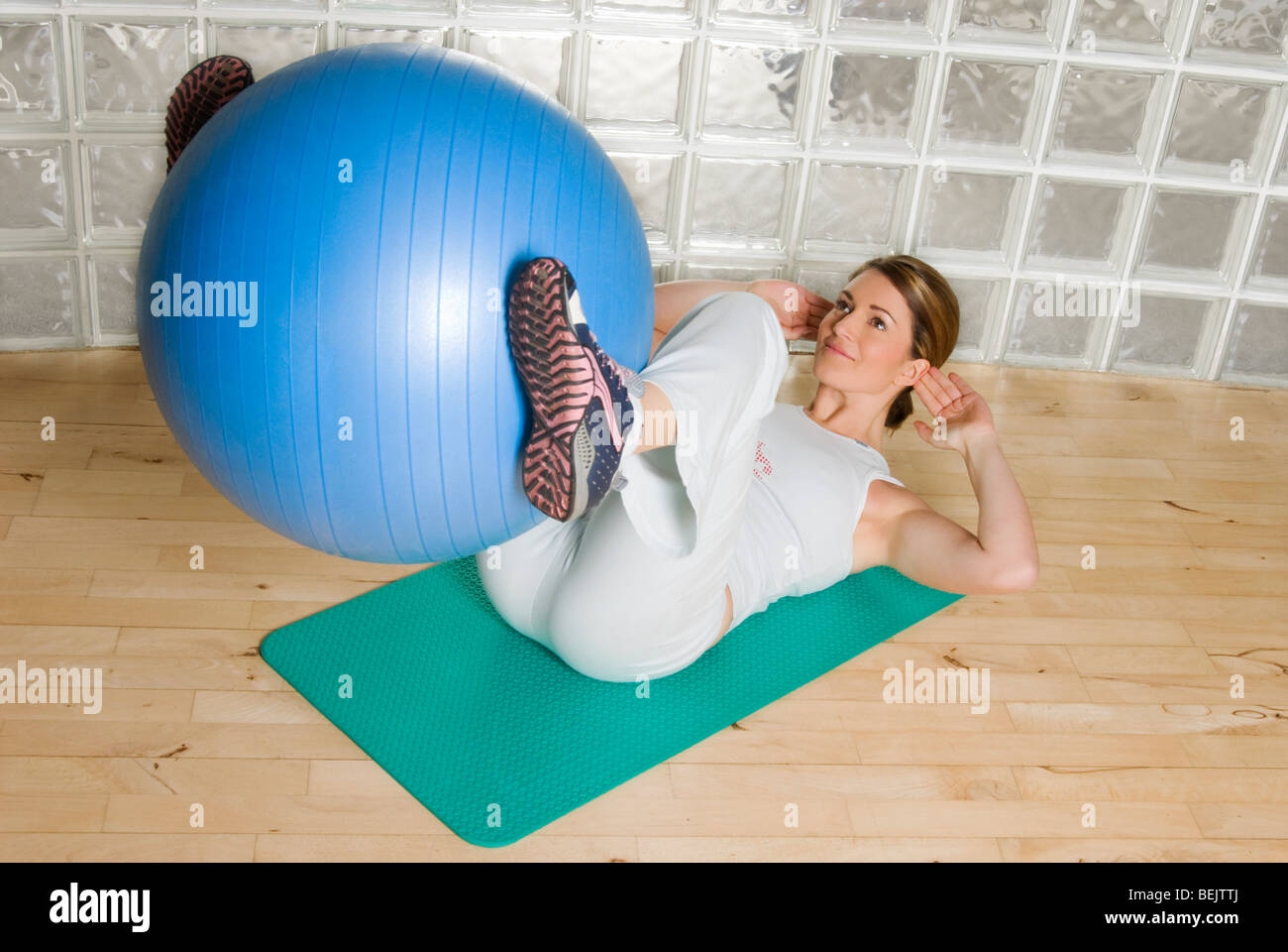 Woman using exercise ball to train / work out in a gymnasium Stock Photo