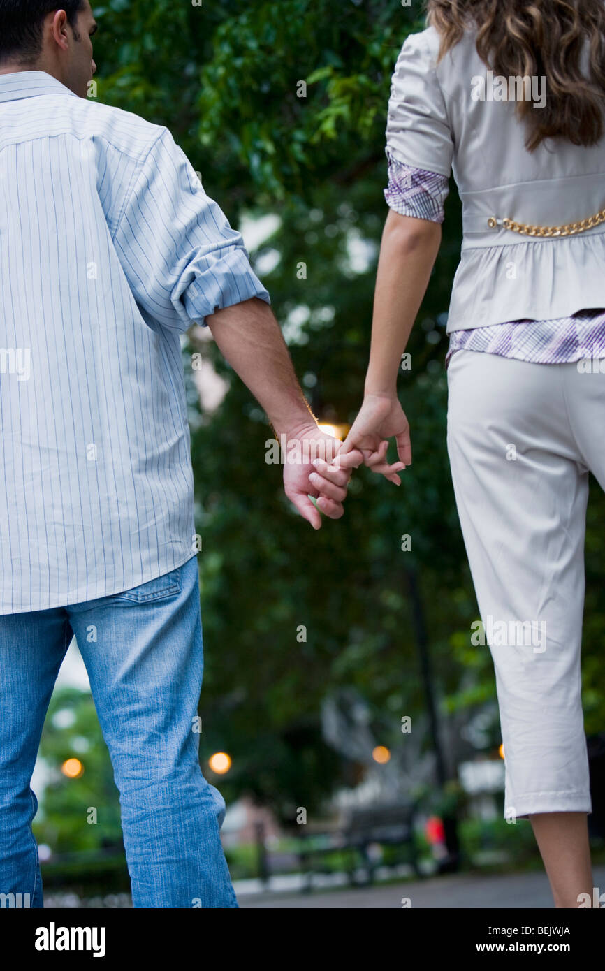Rear view of a young couple holding hands of each other Stock Photo - Alamy