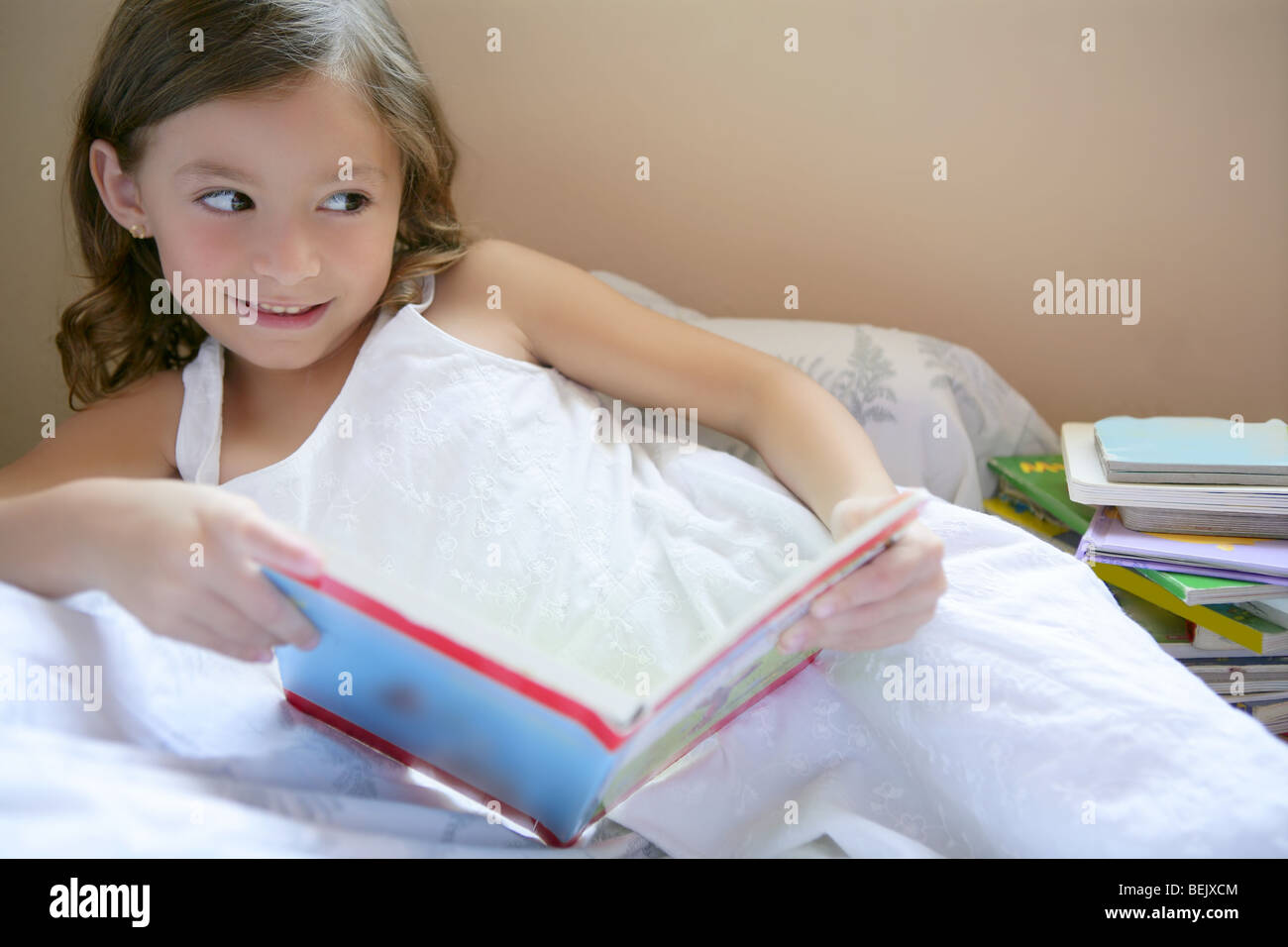 Beautiful little girl reading book at home Stock Photo - Alamy