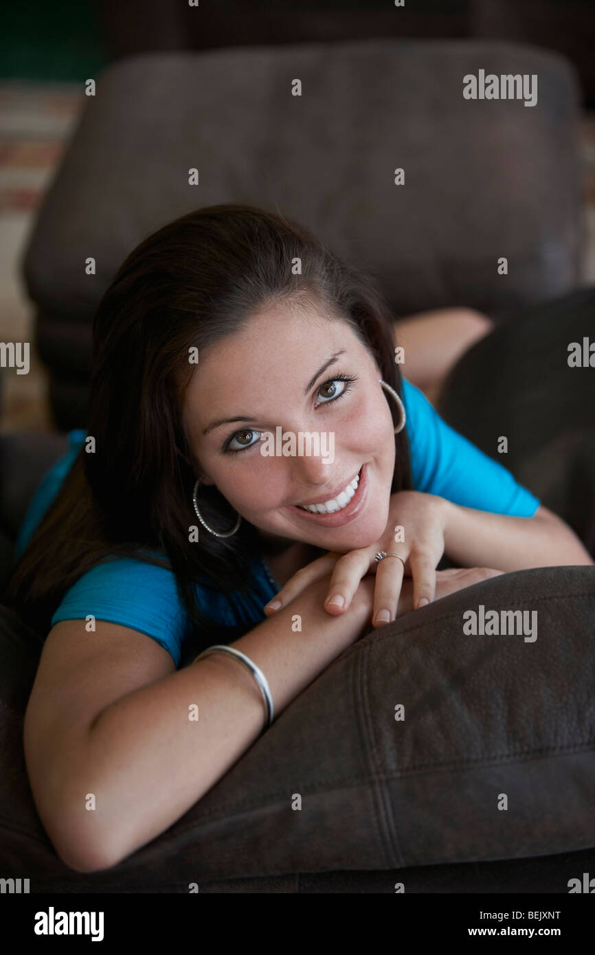 Portrait of a young woman lying on a couch and smiling Stock Photo - Alamy