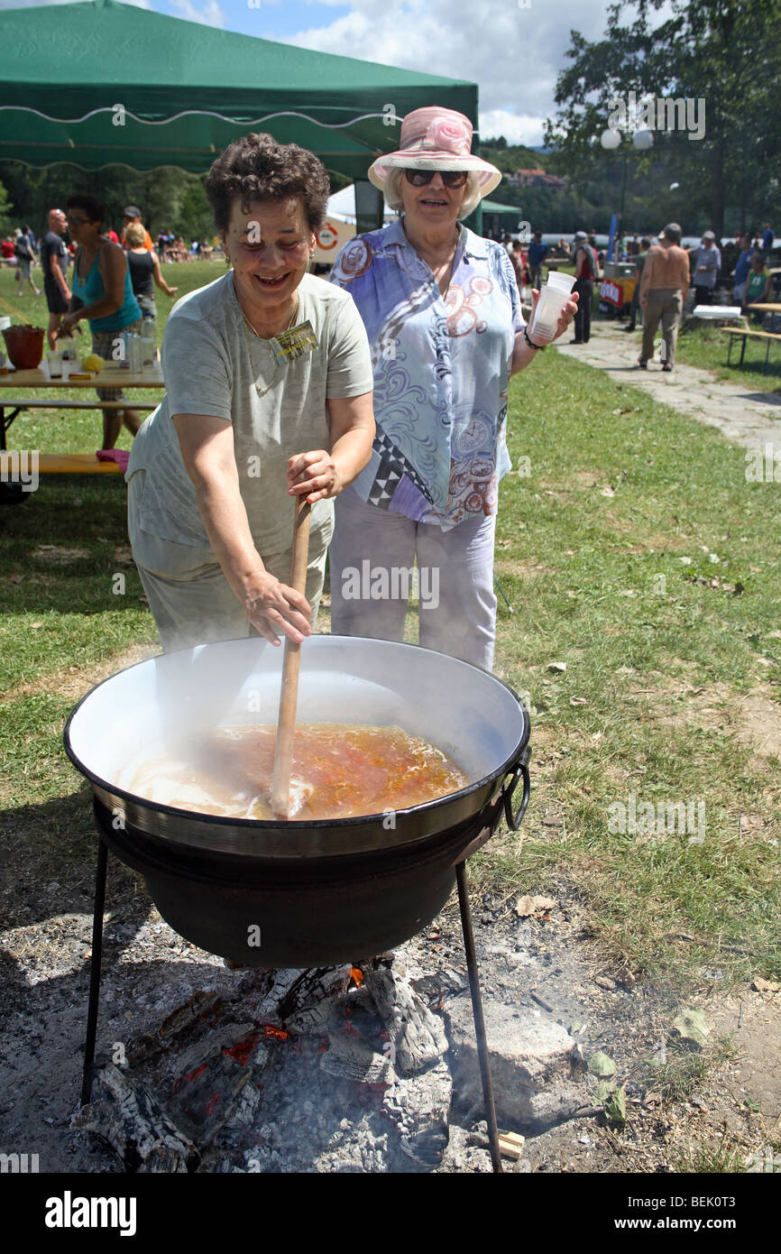 Cookout. Female cook steers been soup in large cooking pot outdoor Stock  Photo - Alamy