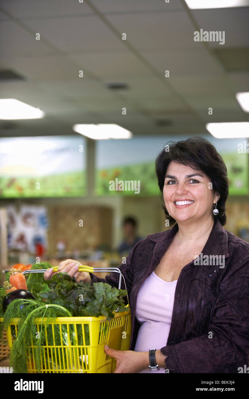 Portrait of a mature woman holding a shopping basket and smiling Stock ...