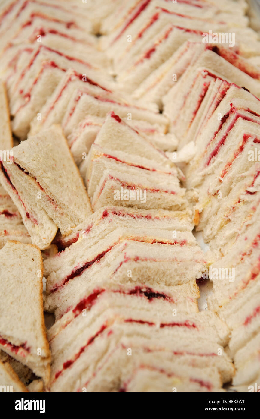 Lots of cut white bread strawberry or raspberry jam triangular sandwiches ready for a childs birthday party Stock Photo