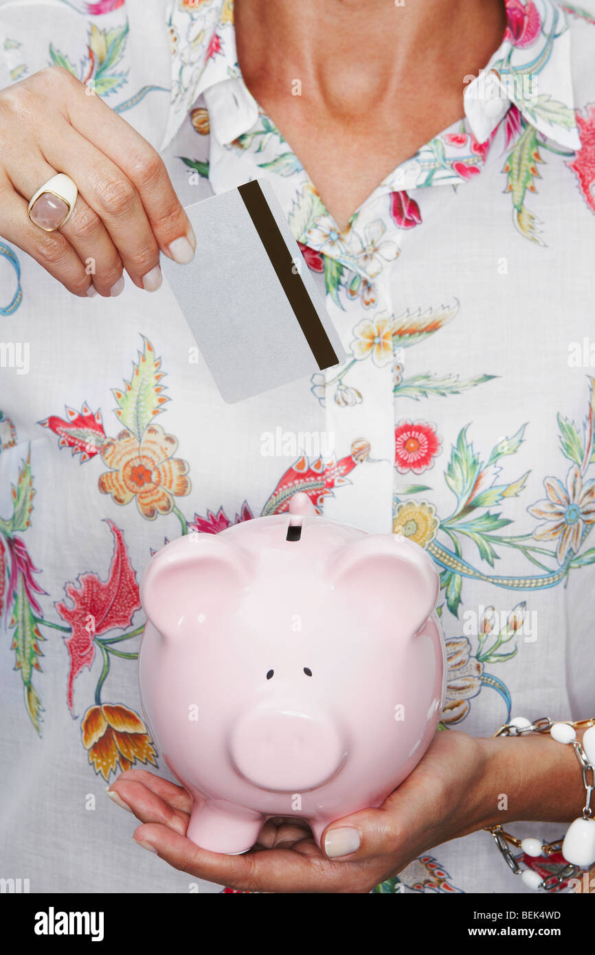 Mid section view of a woman putting a coin into a piggy bank Stock ...