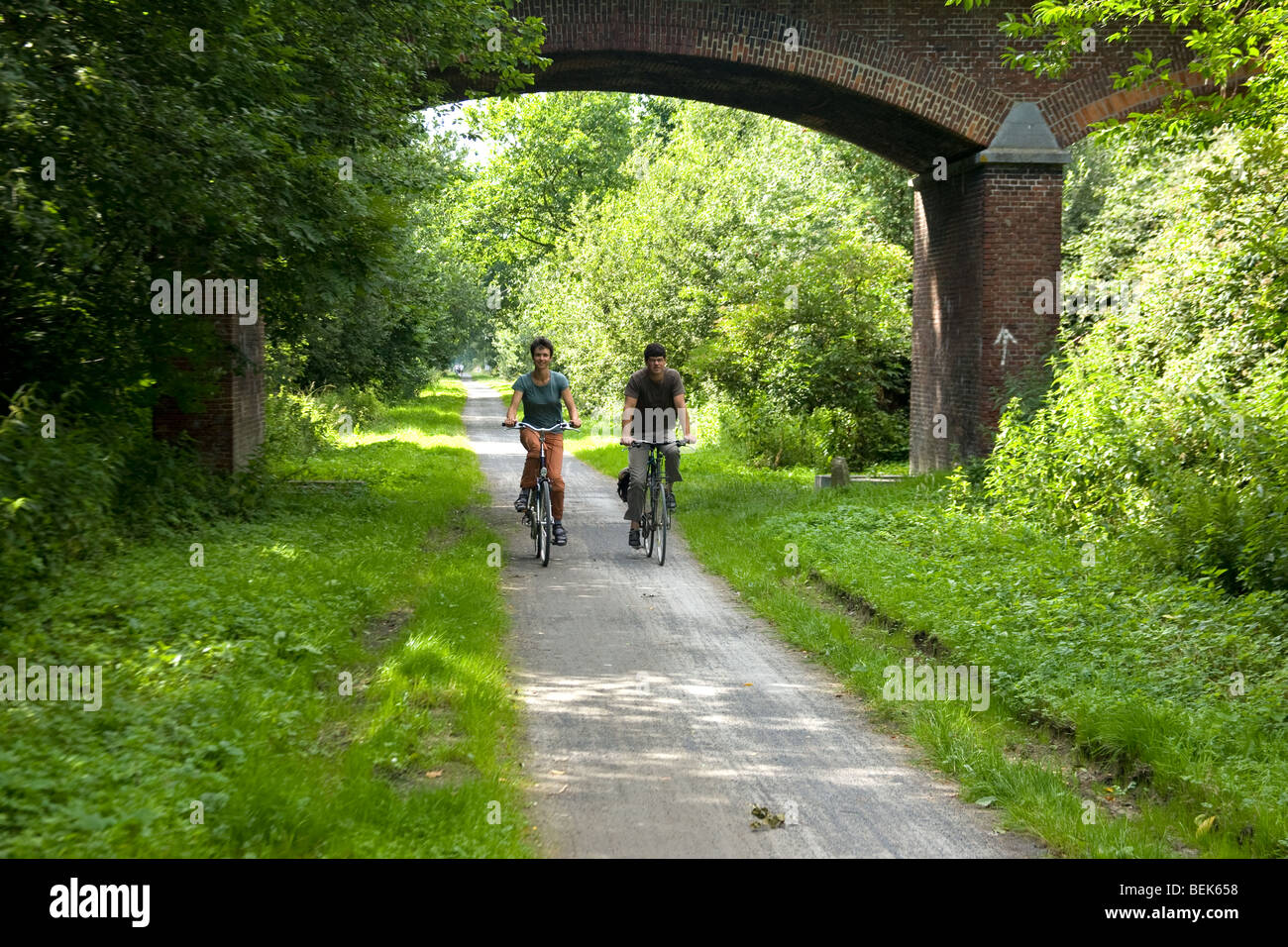 Two cyclists cycling along the old railway the Groene 62, between Torhout and Ostend, Belgium Stock Photo