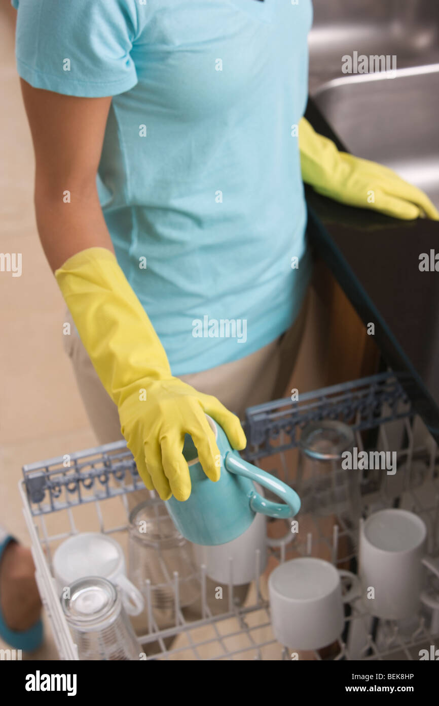 Teenage girl loading dishes into a dishwasher Stock Photo