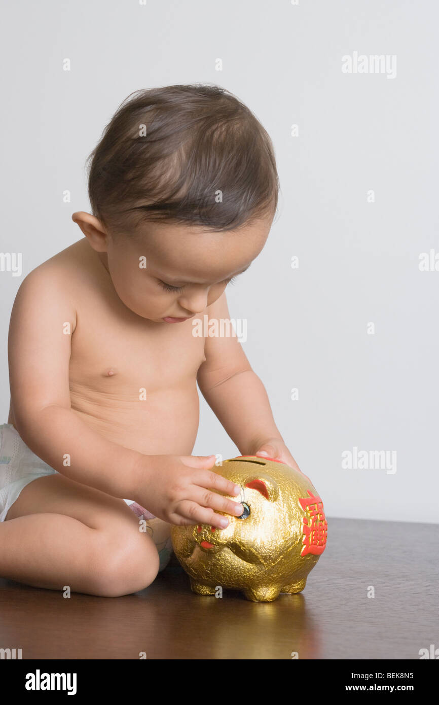 Baby boy playing with piggy bank Stock Photo