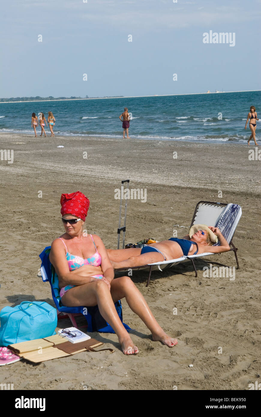 Women sunbathing wearing a bikini and red turban hat, headwear. Venice Lido, an Italian public beach. Venice Italy 2009 2000s HOMER SYKES Stock Photo