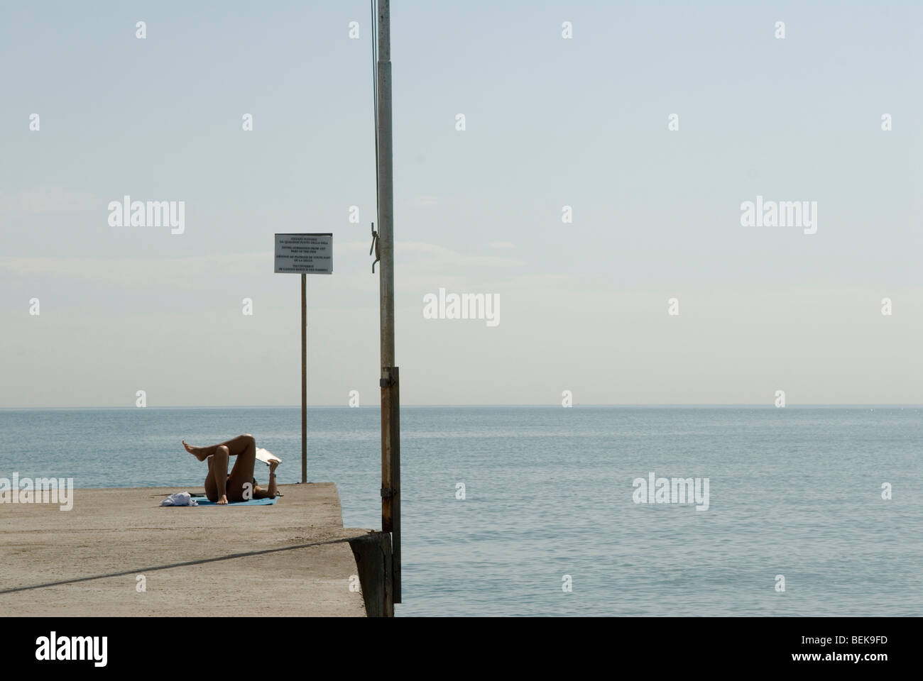 Venice Italy Venice Lido Adriatic sea the public beach. Woman reading sunbathing avoiding other people on holiday. 2000s HOMER SYKES Stock Photo