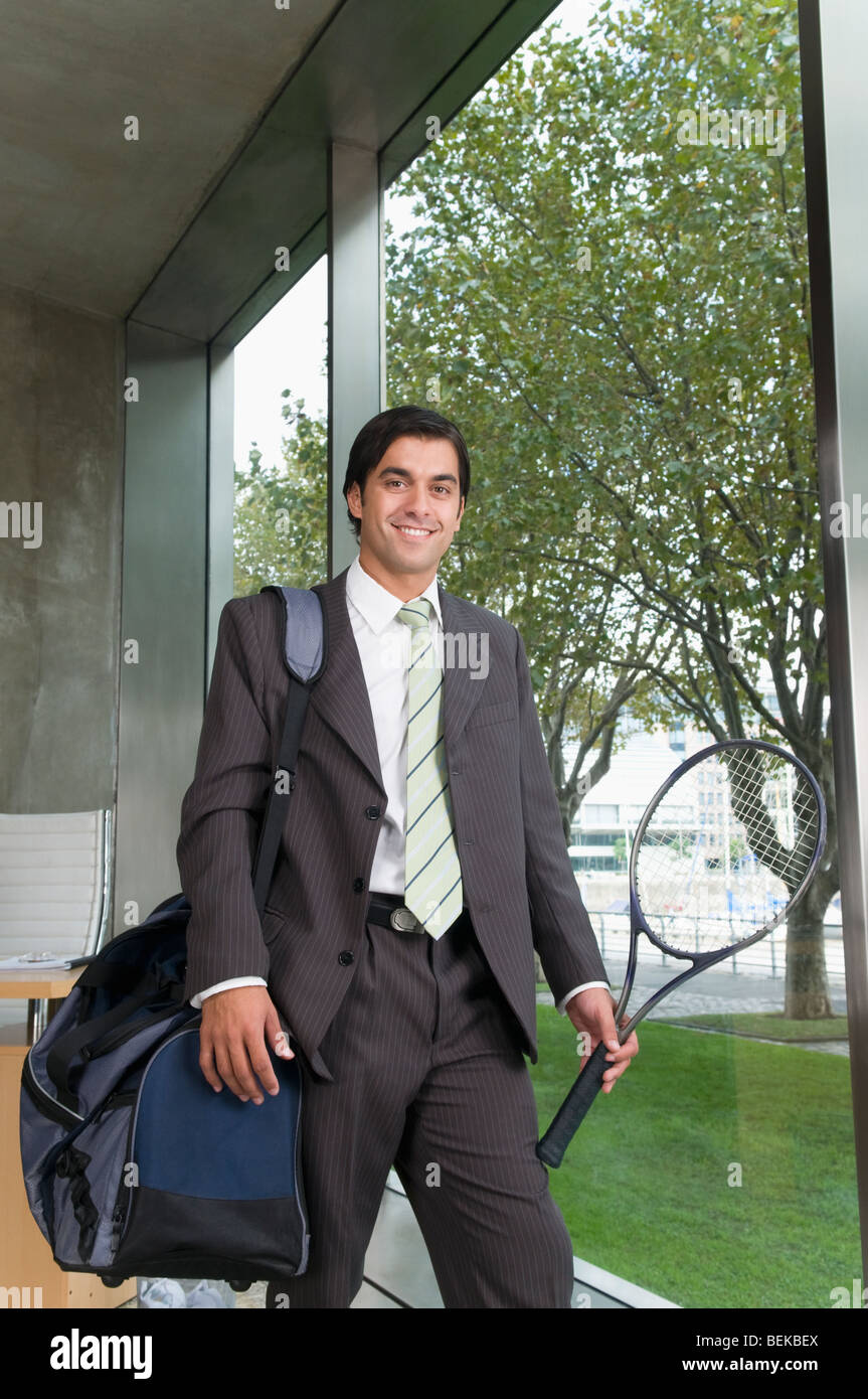 Businessman carrying a bag with a tennis racket Stock Photo Alamy