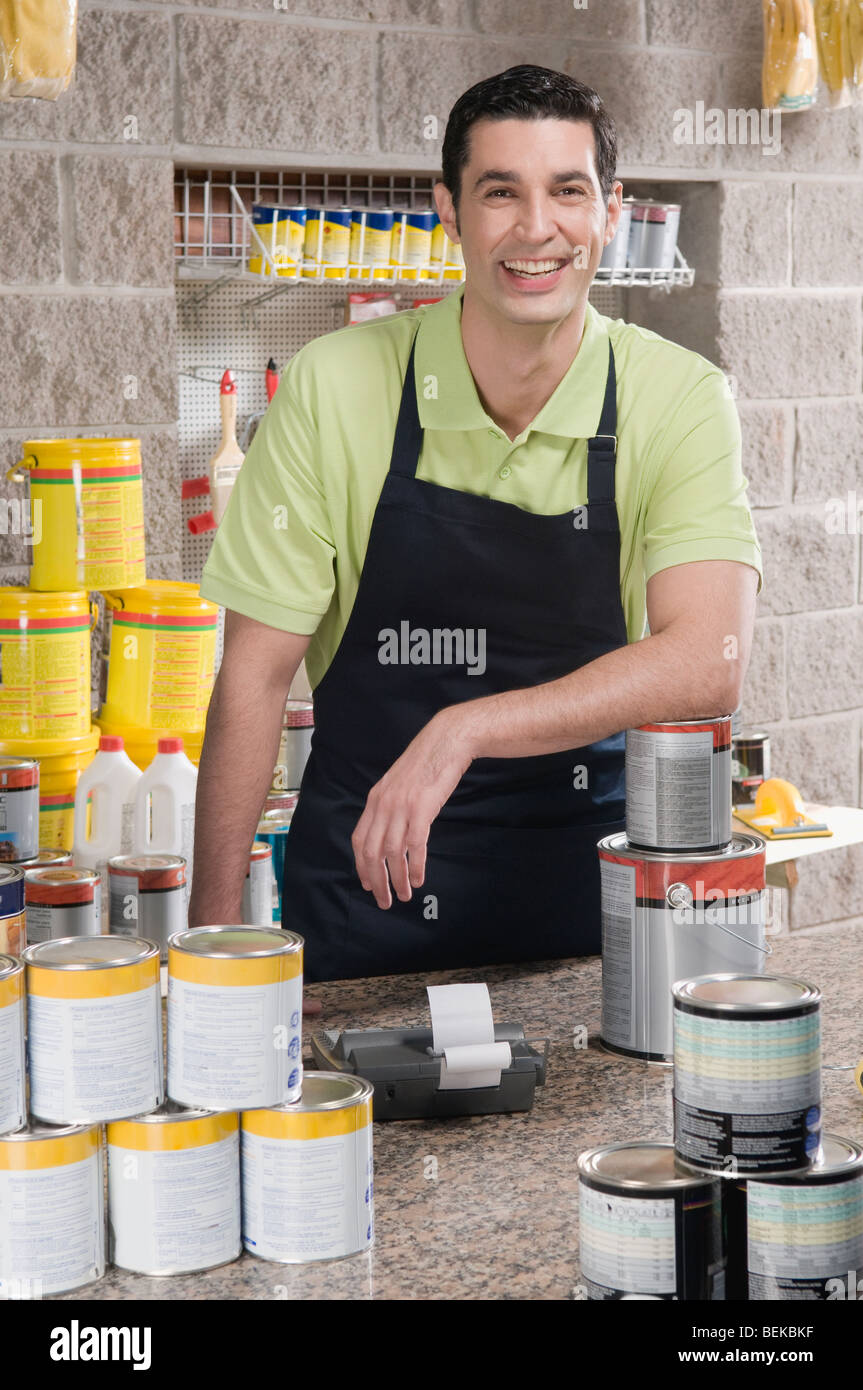 Sales clerk standing at the counter of a paint shop and smiling Stock Photo