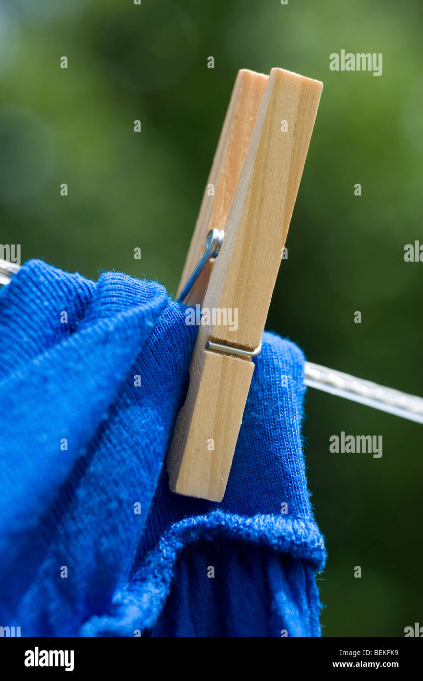 wooden peg holding blue woolen sweater on washing line Stock Photo