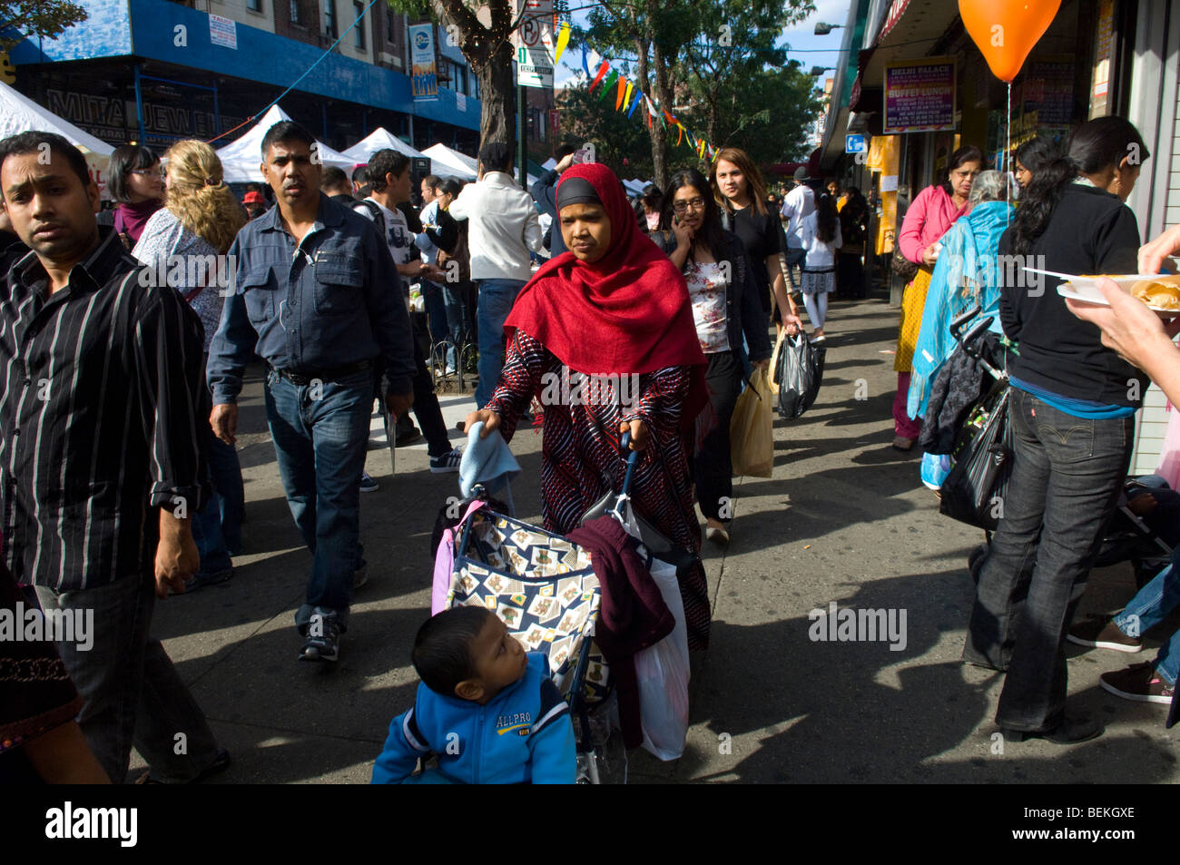 A Moslem woman pushes a child in a stroller at the Indian celebration of Diwali at a street fair in Jackson Heights, Queens, NY Stock Photo