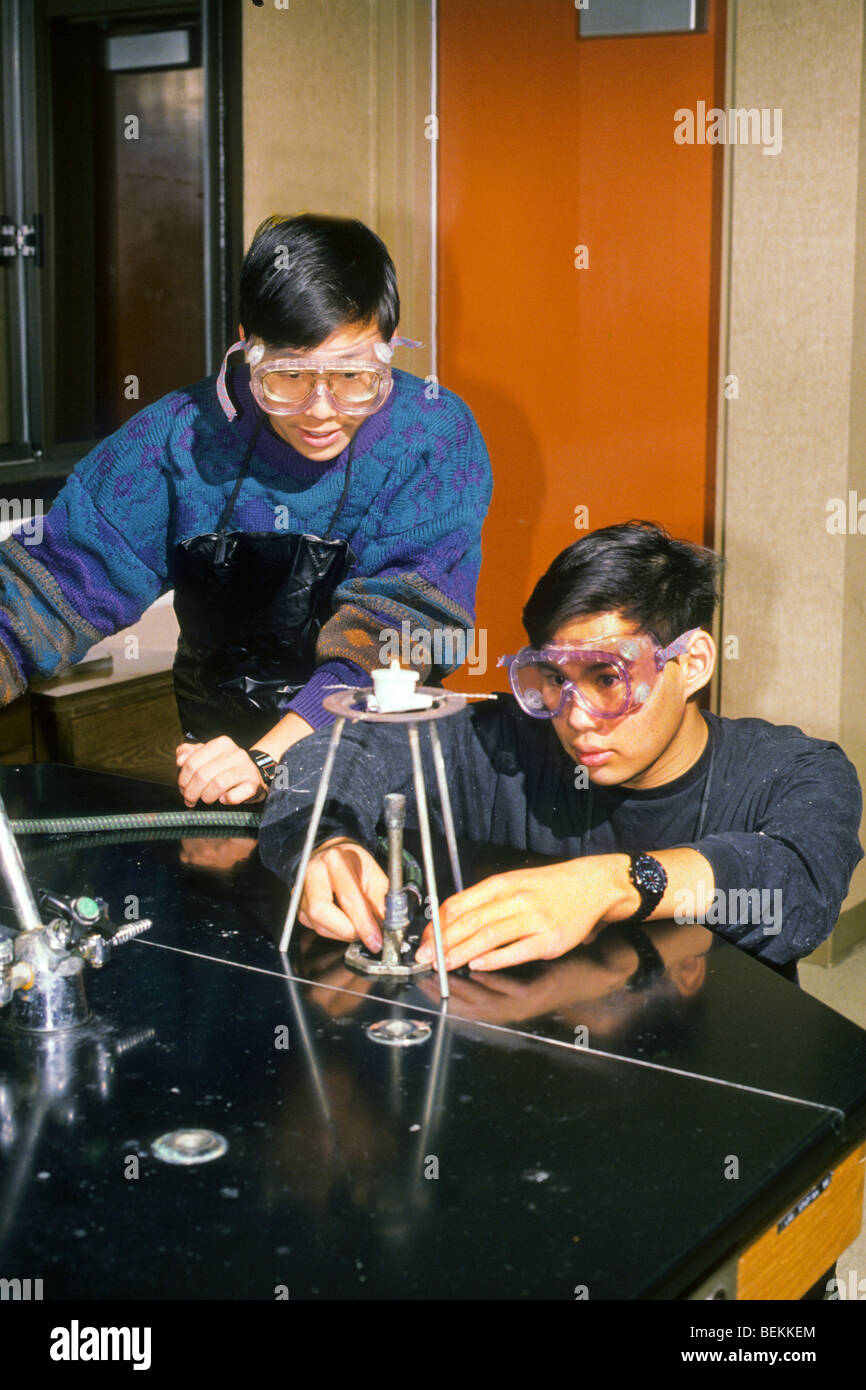 Two teen boys conduct science experiment in class with safety goggles ...