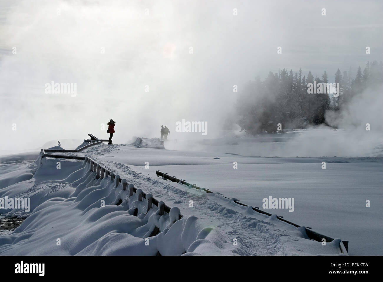 Visitors on boardwalk trail in fog at West Thumb in Yellowstone National Park in winter. Stock Photo