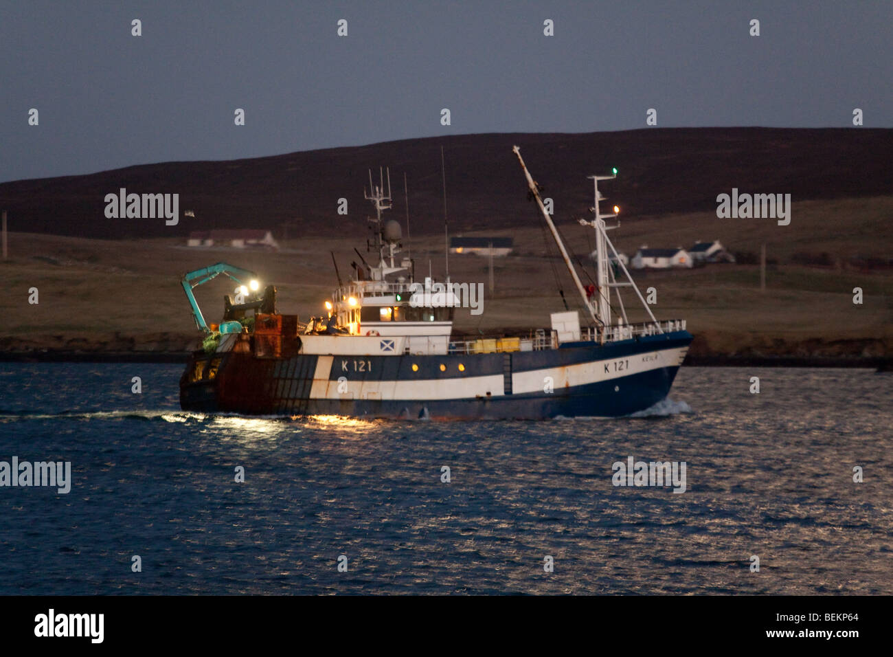 Fishing trawler sailing out on the North Sea at dusk from Lerwick, Shetland. Stock Photo