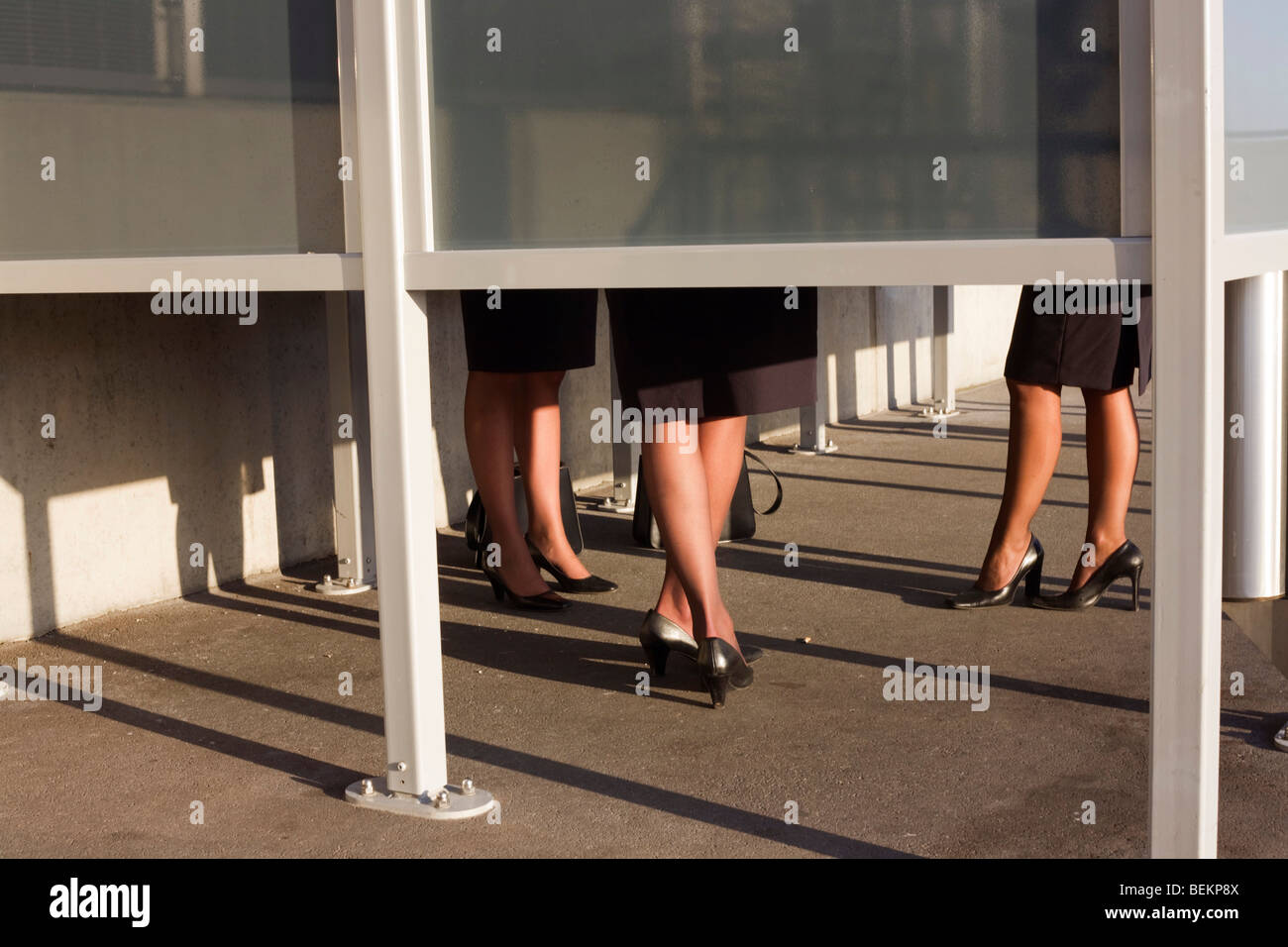 The legs of anonymous airline employees are seen from below a smoking screen that obscures their faces outside Heathrow Airport Stock Photo
