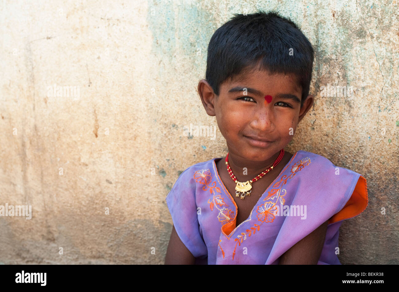 Young Indian street girl smiling leaning against a wall in India, with copy space. Stock Photo