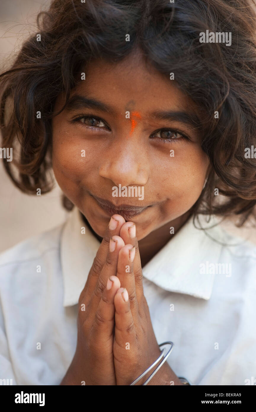 Young Indian street girl greeting with folded hands and a happy smiling face. Selective focus. Stock Photo