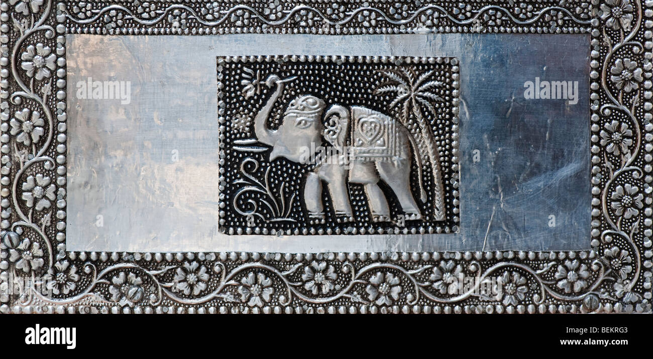 Indian metal craft work. Picture of an elephant and flowers on the side of a metal box. Panoramic Stock Photo