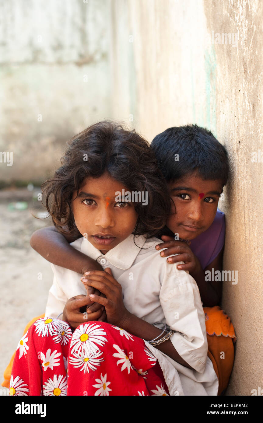 Young Indian street girls smiling and hugging leaning against a wall Stock Photo