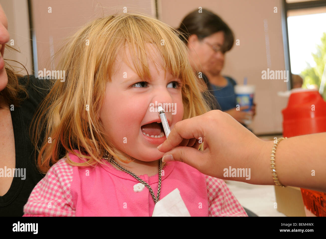 A 4-year-old girl is vaccinated for the 2009 H1N1 influenza, also known as the Swine Flu, with an intranasal vaccine. Stock Photo