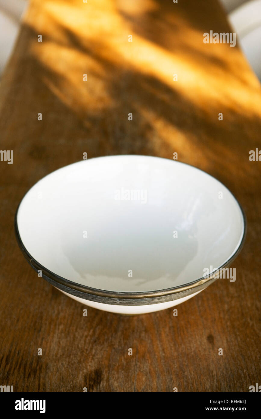 Ceramic bowl with metal rim on wooden table Stock Photo